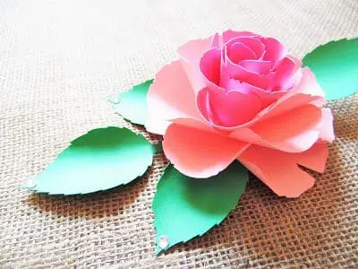 The paper Ruby Rose and matching paper greenery sits open on a piece of tan canvas. Paper flowers are easy and fun to make with my templates. 