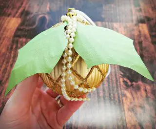 In Abbi Kirsten's hand is the gold ornament, with paper leaves and a string of pearls added for a more exciting decoration.