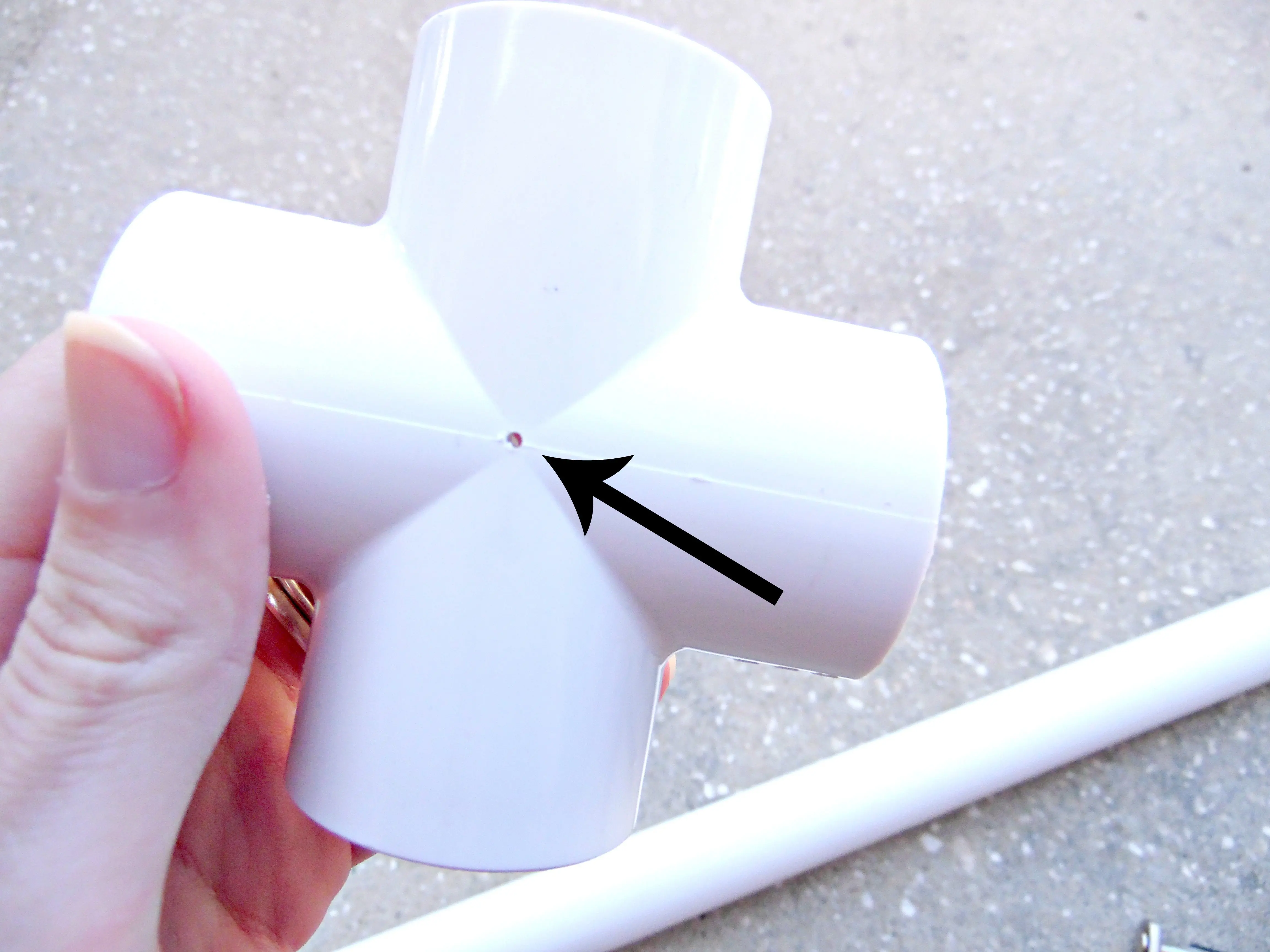 The small hole left by drilling into the PVS 4-way cross using the small drill bit. These pilot holes are the start of a giant paper flower stem display stand.