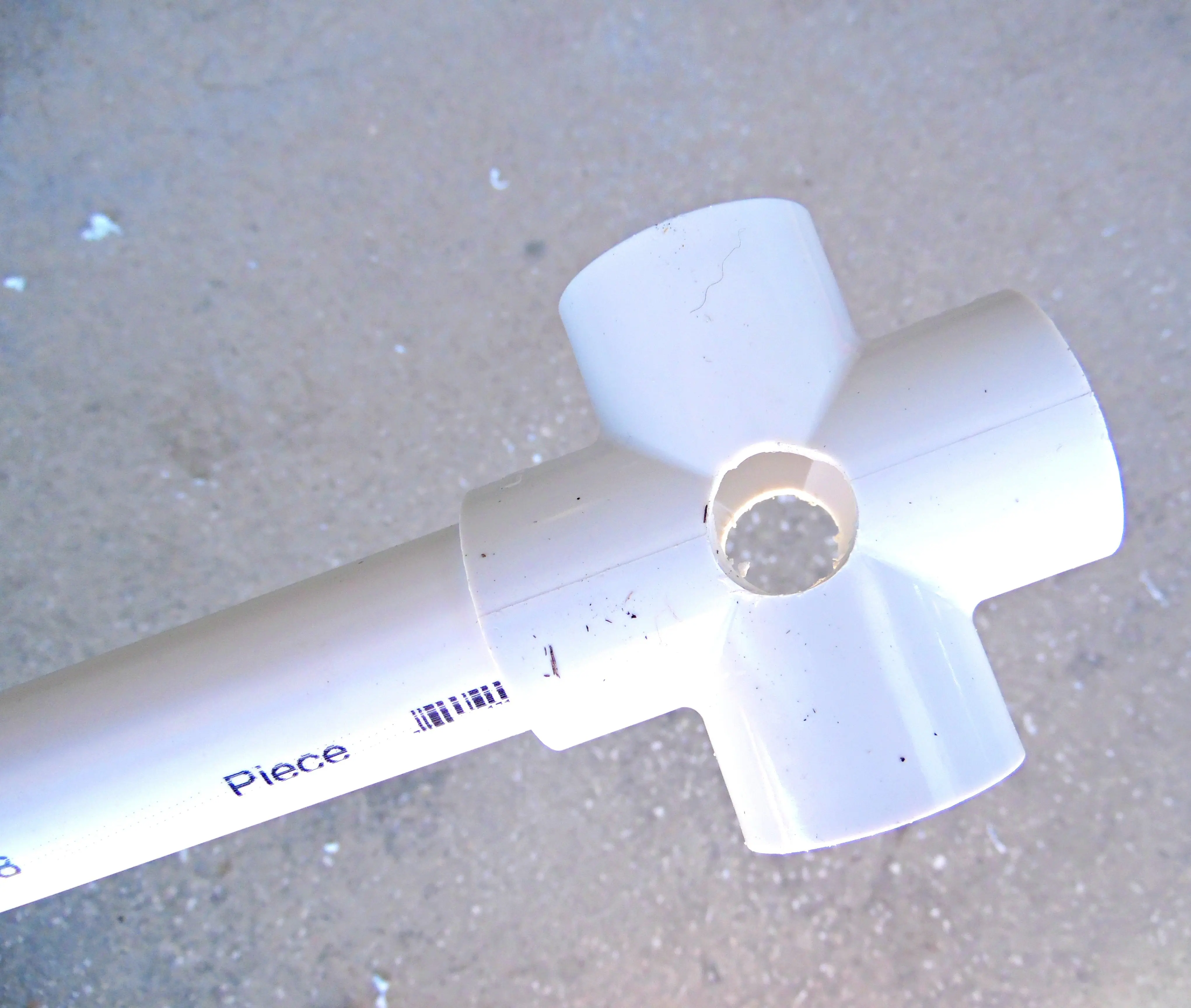 For the giant paper flower stem display stand, place one leg section into one of the holes on the 4-way PVC cross, as seen here.