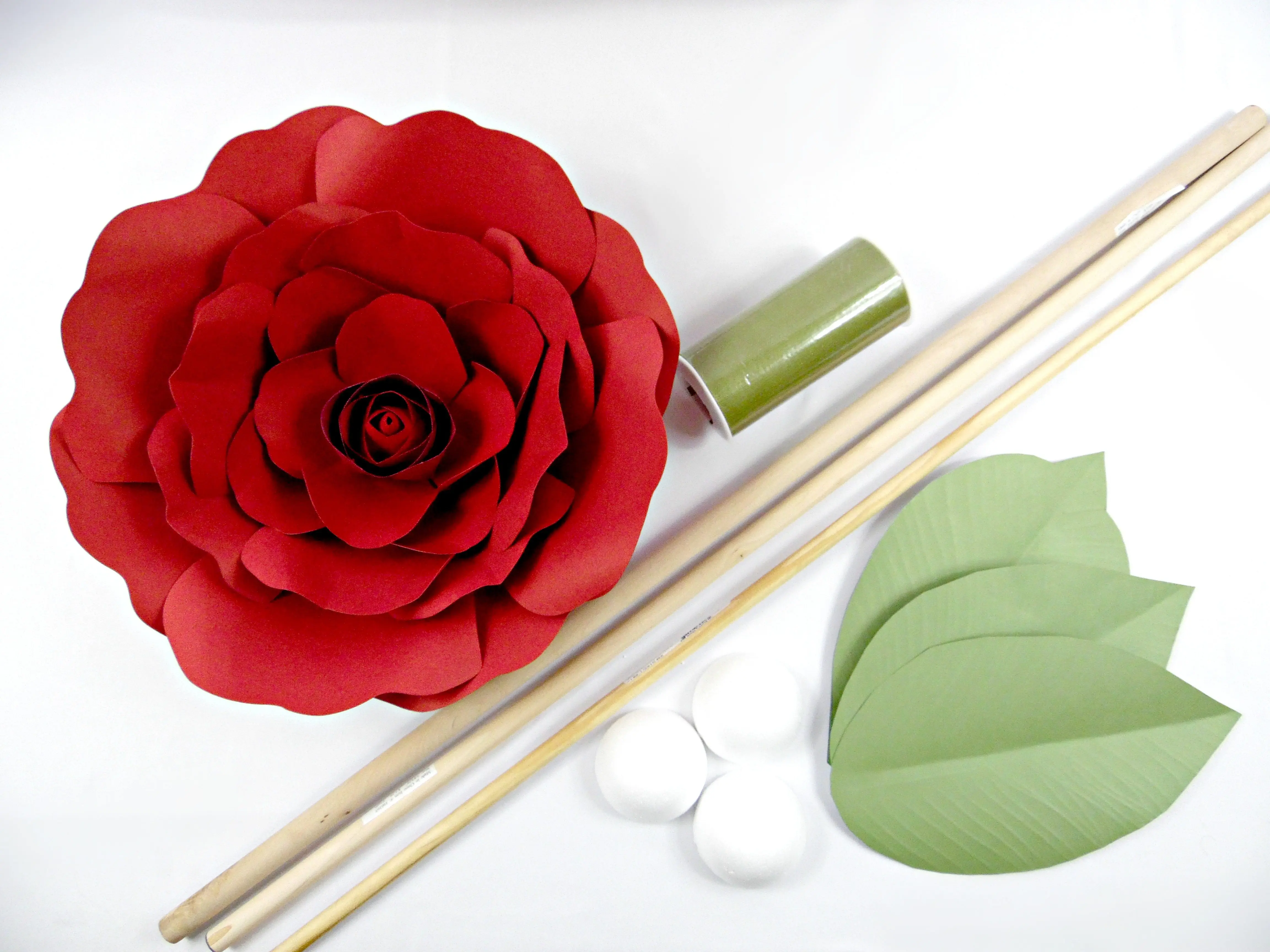 All the supplies needed to make giant paper flower stems: paper flower, leaves, dowel, foam balls, and tulle or paint.