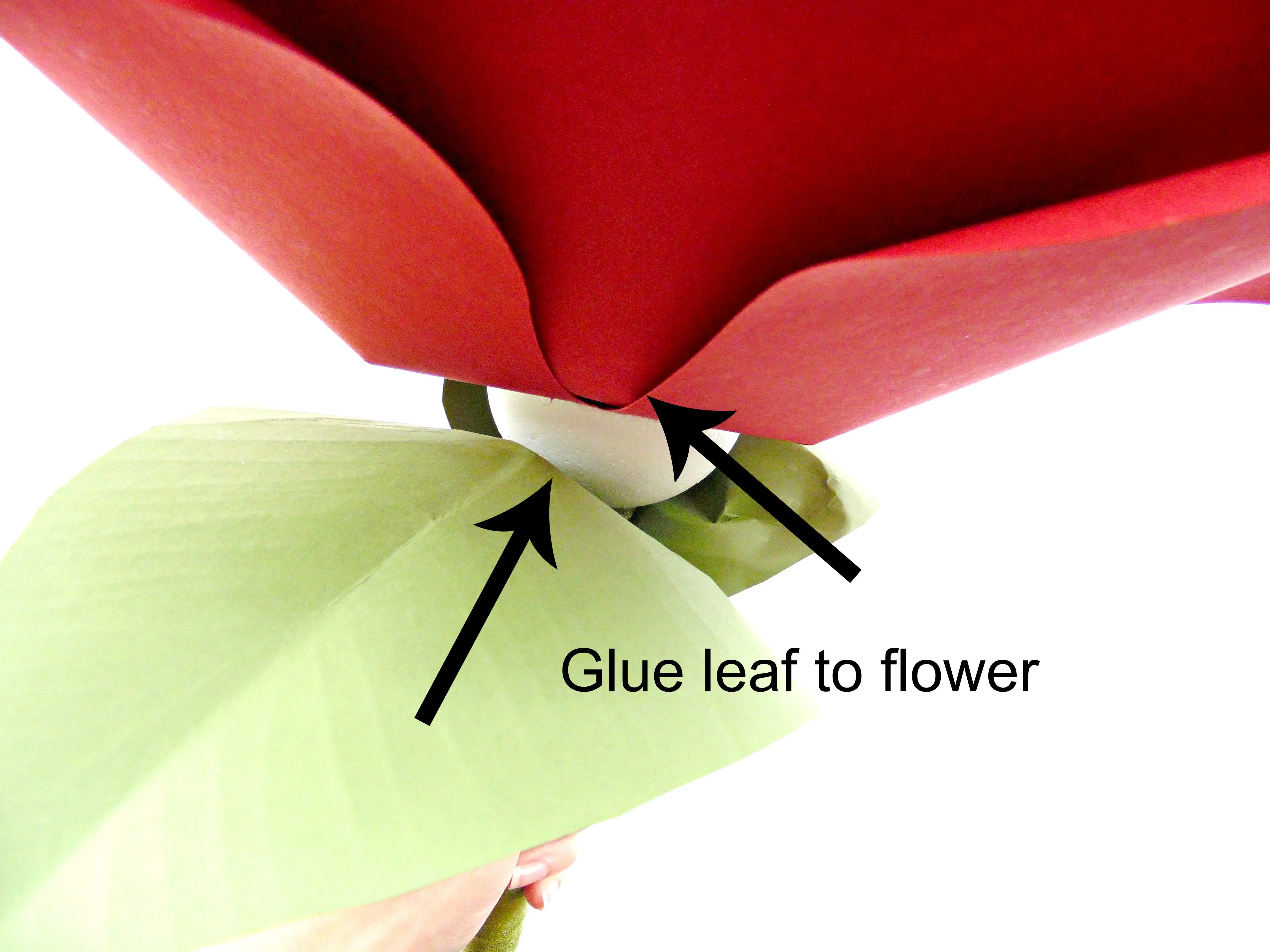 To attach the giant paper flower head to the foam ball and flower stem, use hot glue and press the flower head firmly to the foam ball.