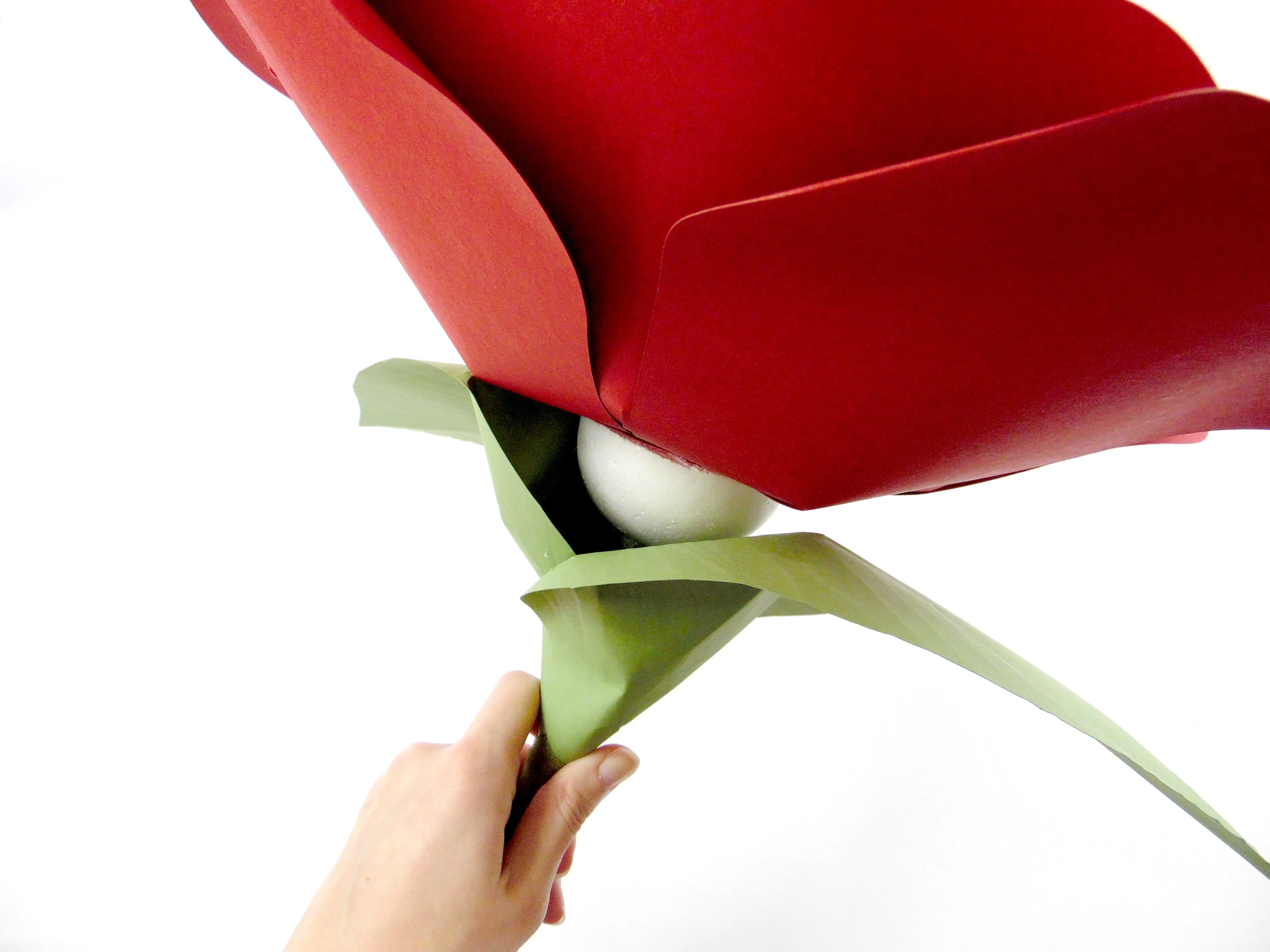 Two leaves surround the foam ball, which we've attached with hot glue to the giant red paper flower head.