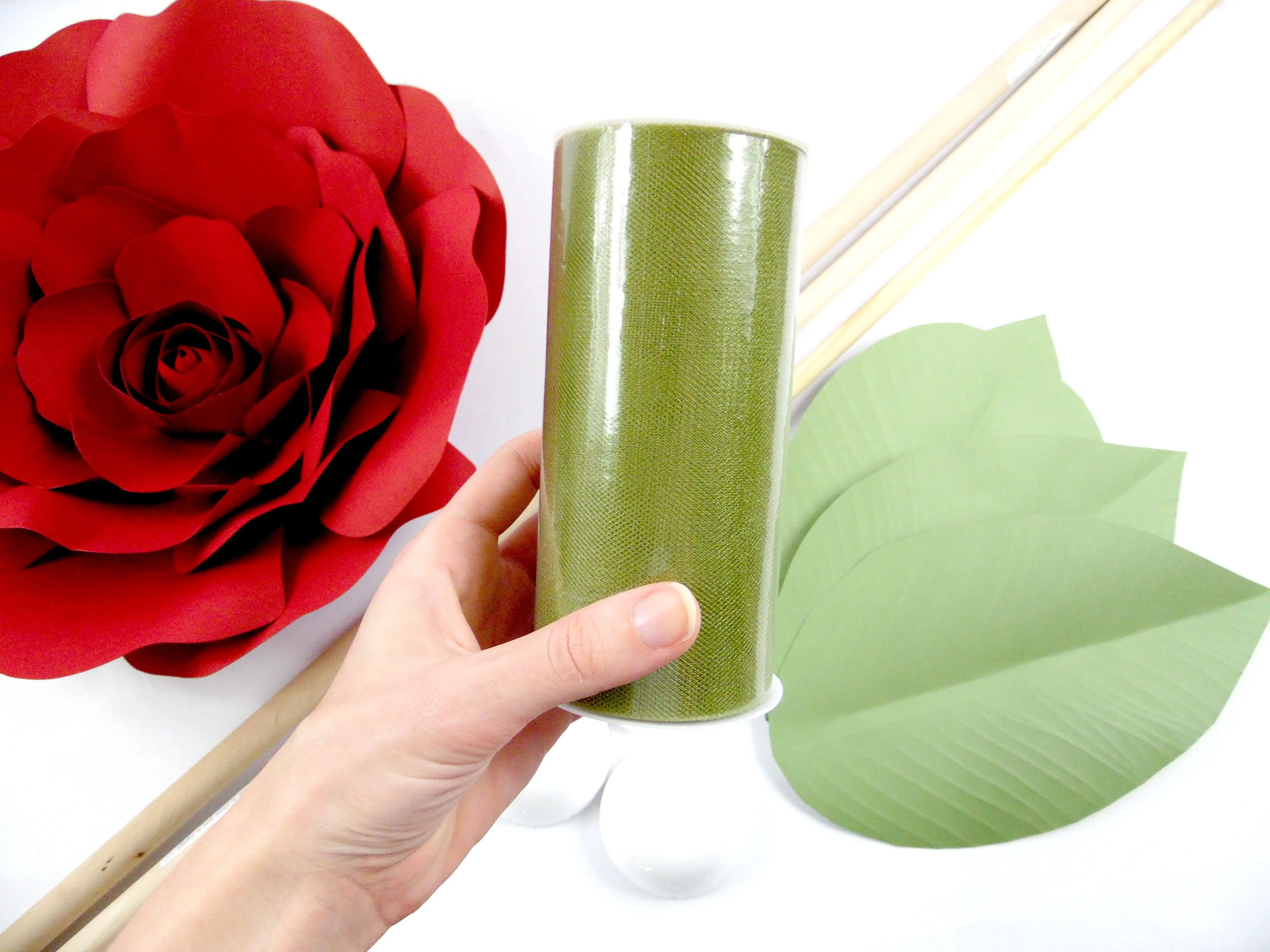 In this giant paper flower stem tutorial, I use green tulle to wrap around the dowel, matching the yellow-green color of natural flower leaves.