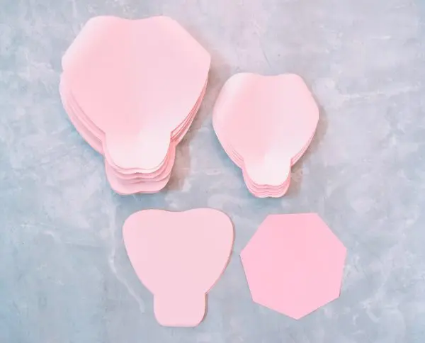 Extra-large and large pink paper rose petals have been prepared and are stacked next to the pink paper rose base.