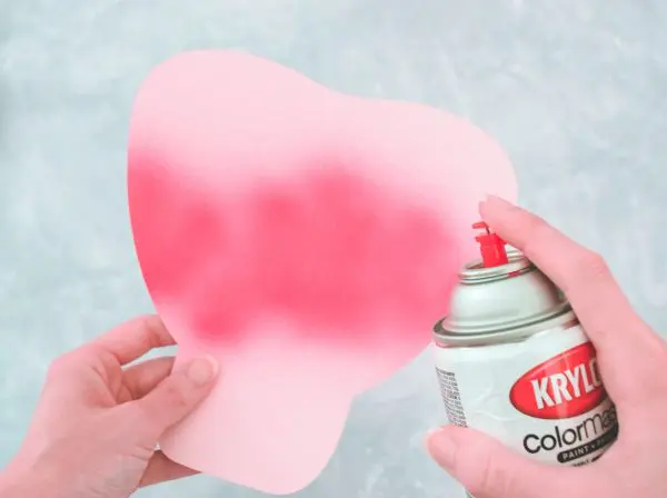 Abbi uses spray paint to create a darker pink center on a light pink petal for the Alora garden rose. 