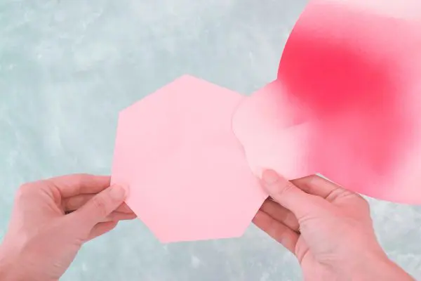 Abbi glues the curled, giant Alora garden paper rose petal to the flower base. 
