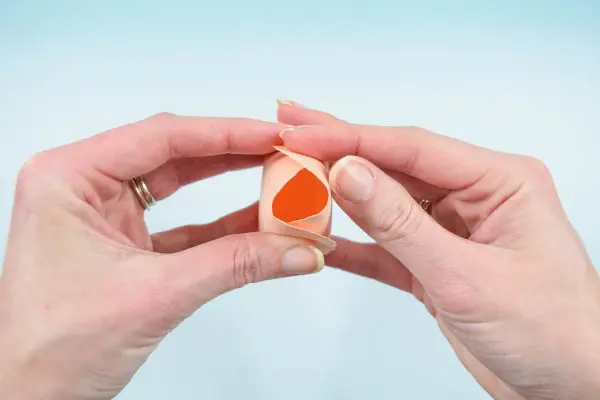 A close-up of Abbi Kirsten as she folds up the two connected paper petals to form the center of a paper rose center. 
