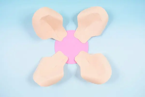 Four paper rose petals have been glued around a pink paper circle laying on a blue background. This is the base and outer layer of the DIY paper rose serena flower.
