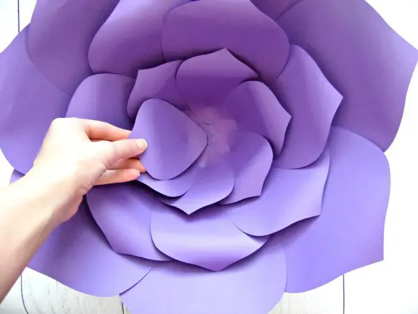 Abbi's hand reaches into the giant paper flower to add the final purple petal in the inner third layer.