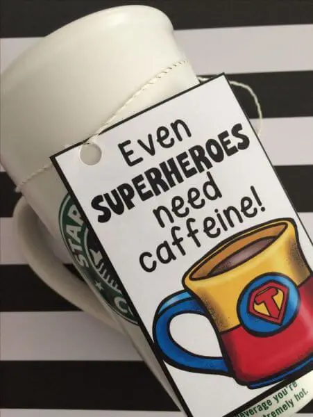 A reusable Starbucks coffee mug with a cute gift tag attached that reads