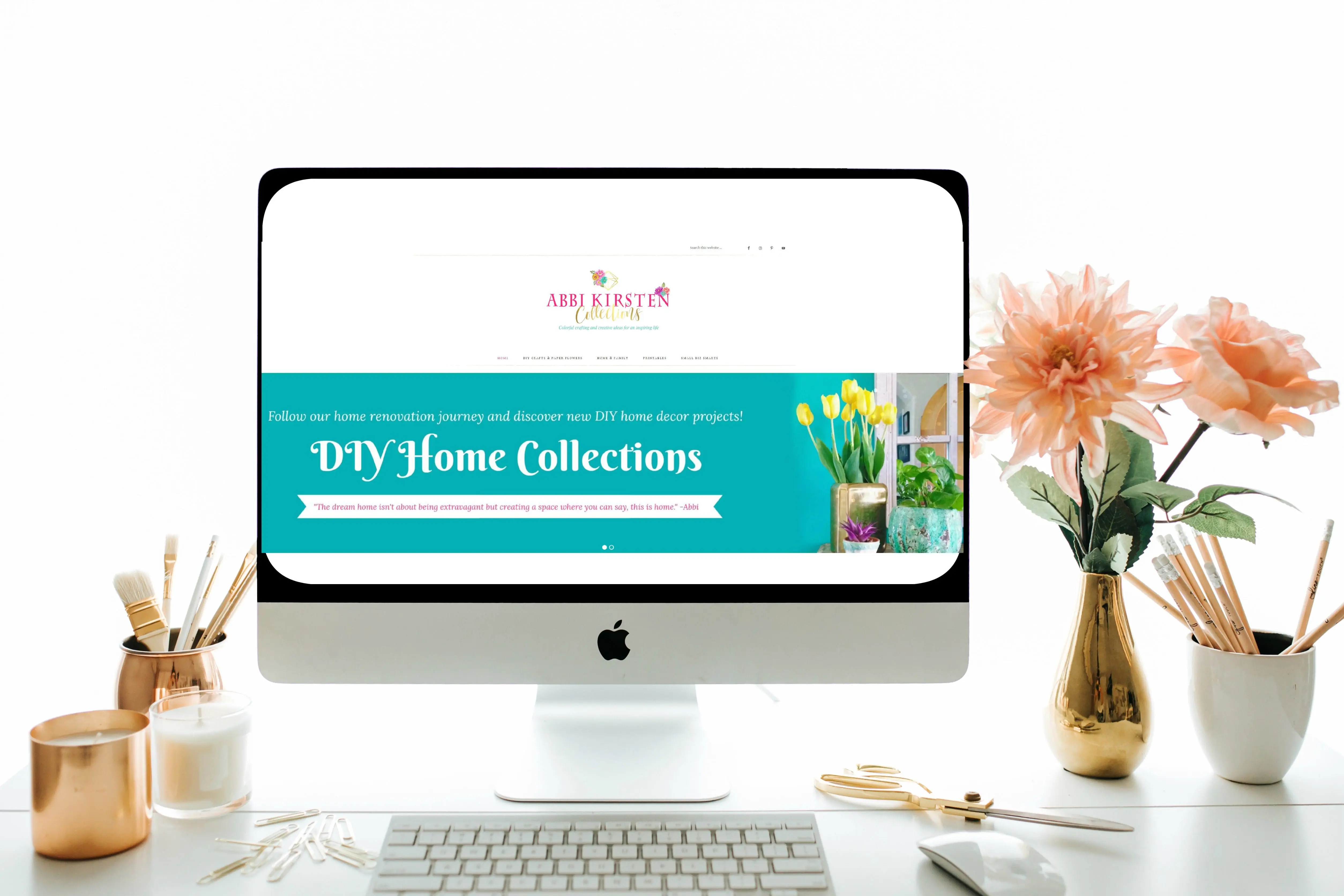 An office desk set up include a desktop computer with office supplies and a vase of flowers. A website homepage is displayed on the computer screen.