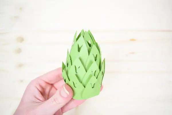 A hand holding a giant green paper stamen for a magnolia. 