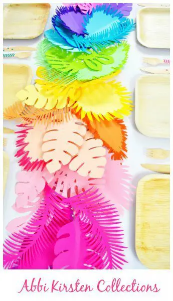 A bright rainbow paper leaf table runner next to bamboo place settings. 