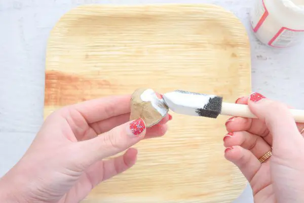 Cover the detached paper mache pumpkin stem with mod podge using a sponge brush.