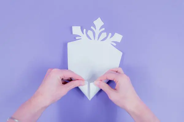 Abbi demonstrates how to fold the bottom of the paper snowflake petals into a cone shape.