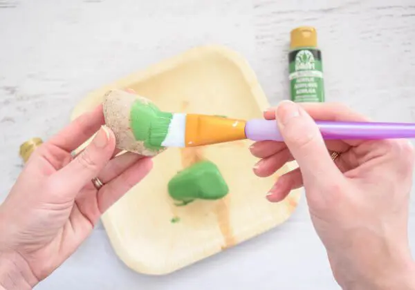 A rock being painted light green. 