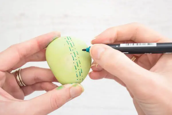 Green dots and dashes added to a light green rock. 