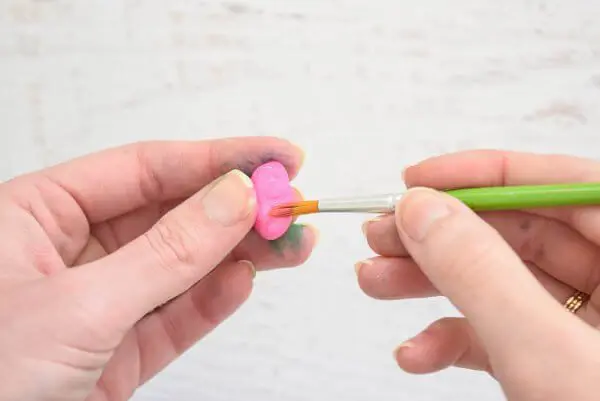 A small rock being painted pink. 