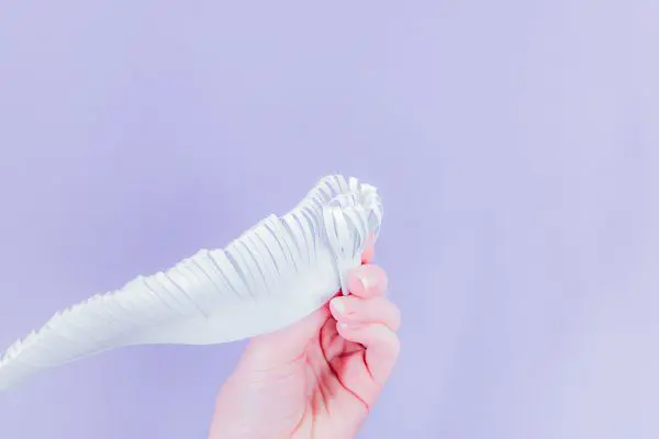 Abbi demonstrates how to roll the fringe paper to create a fringe center for the paper snowflake.