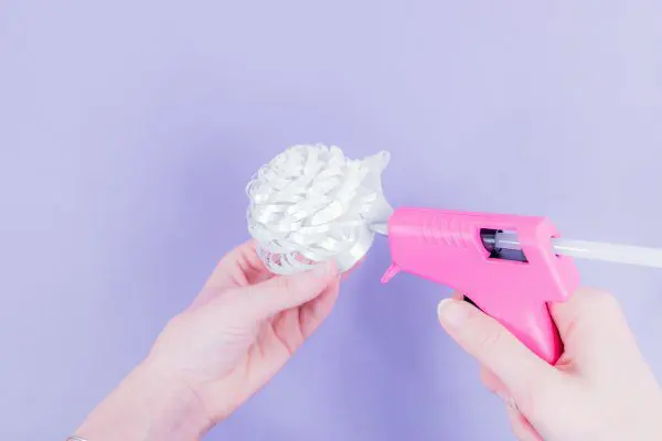 Abbi demonstrates how to roll and glue the fringe center for the giant paper snowflake.