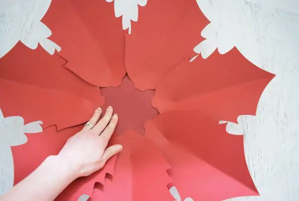 Seven large poinsettia flower leaves glued to a red base, making the base of a large Noel Poinsettia flower.