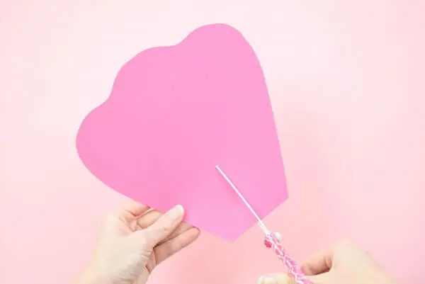 Abbi Kirsten holds an extra-large pink petal as she cuts a slit from the bottom to the middle of the paper flower.