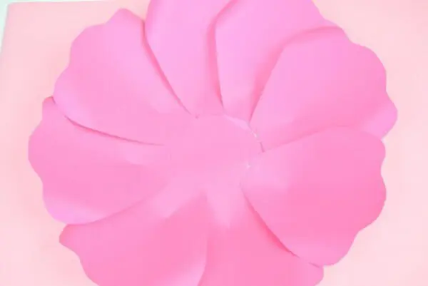Making paper flowers begins with this finished bottom layer of pink paper petals. The petals are glued to a base and overlap counter-clockwise.