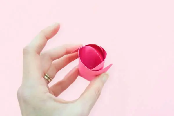 Abbi Kirsten's hand holds the beginning of a pink rosebud almost ready to be glued into the paper Penelope rose.