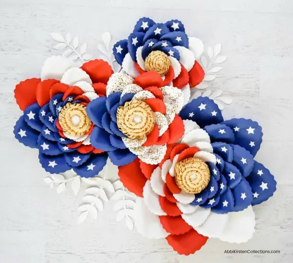 An overhead view of a bunch of flowers with red petals, white petals, and blue with white stars petals. These giant American flag paper swirl flowers will be the highlight of any picnic table during a 4th of July celebration.