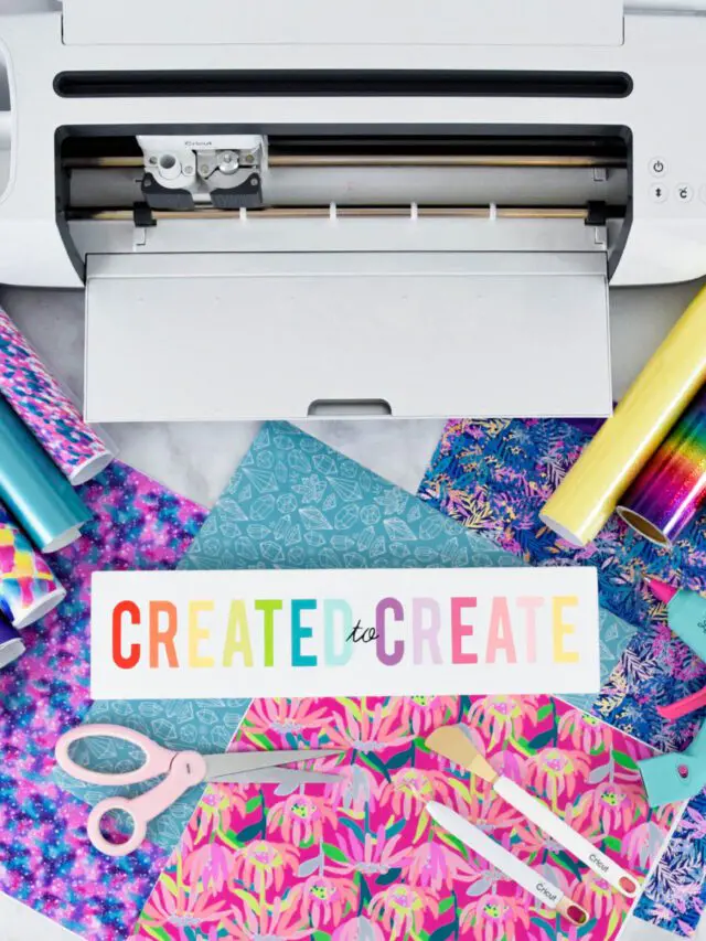 Cricut maker machine open on a desk with cricut vinyl and other tools and materials around.