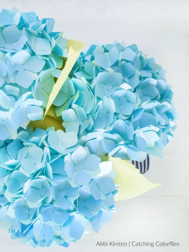 Overhead shot of a bunch of powder blue paper hydrangeas on a white vase