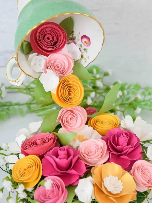 A floating teacup with cascading pink, yellow, red and orange paper roses from it