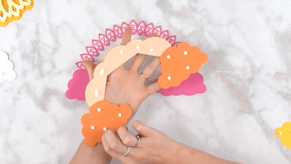 Abbi shows the back of the 3D rainbow mandala craft, speckled with foam tabs  to attach the other layers of the rainbow.