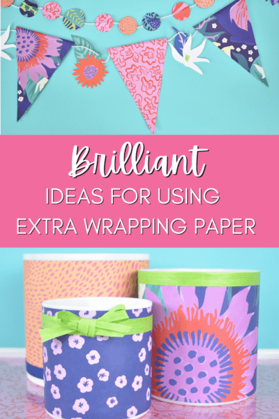 Cylinder vases decorated with brightly colored wrapping paper sitting on top of a pink and red tray table and a wrapping paper banner hanging on a light blue wall. 