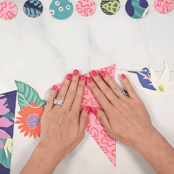 Assembling a banner with colorful wrapping paper, white twine and glue. 