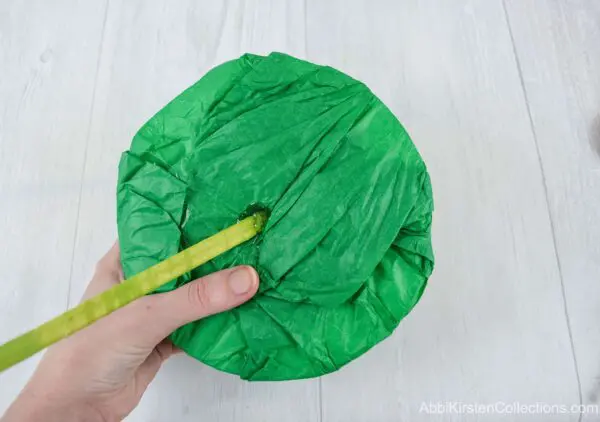 Two dowels wrapped in corsage tape are inserted into a tissue paper covered paper flower bouquet base.