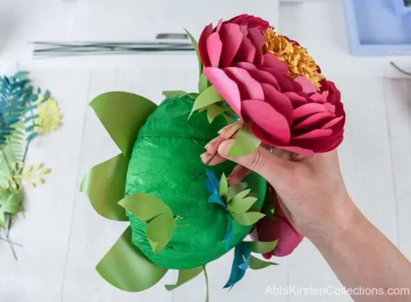 A large paper full bloom red peony is inserted into the foam base.