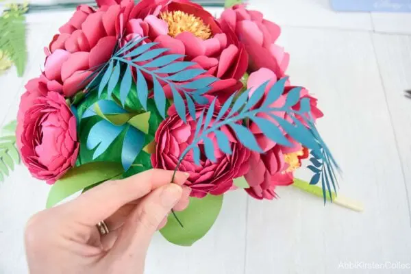 Long paper vines and fern leaves hang down and curve inward to create a waterfall effect.