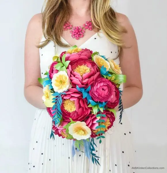A woman holds a DIY cascading paper flower bouquet—a great alternative to the classic floral wedding bouquet. These brightly colored paper flowers have many advantages over real flowers.