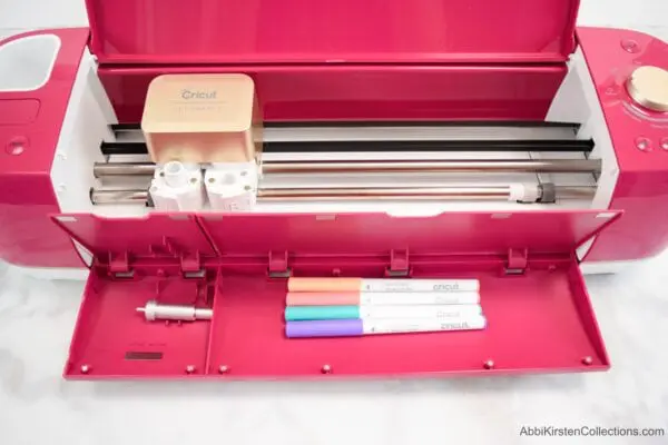 A red, open Cricut Explorer machine as seen from above. This beginner's guide to Cricut cutting machines will help you feel confident about crafting.