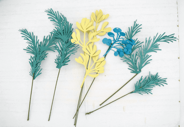 Springs of paper mistletoe leaves and berries made from green, blue, a d gold paper on stems.