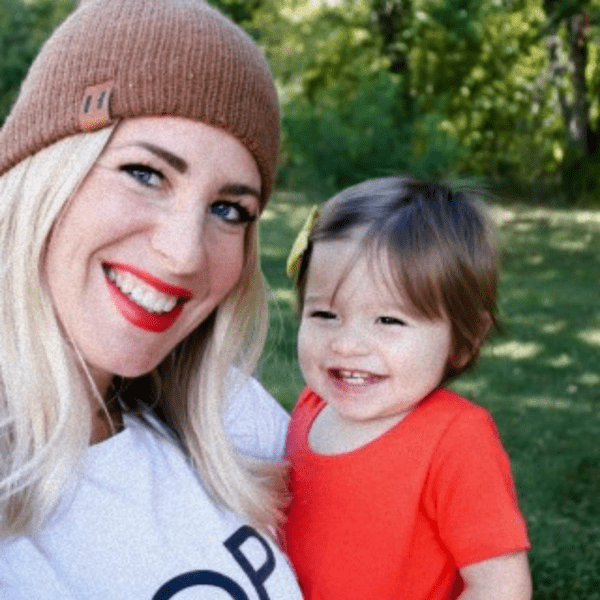Jackie and her baby are smiling in a sunny park, sharing their positive feelings about Abbi Kirsten's Cricut for Beginners Workshop. 