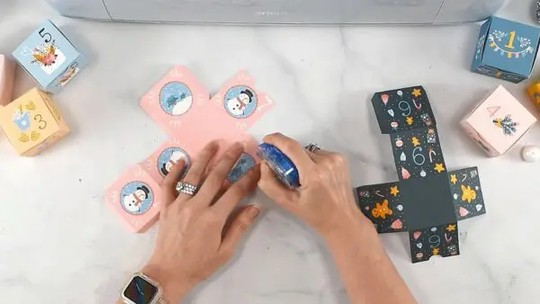 Abbi Kirsten adds adhesive to the edges of the advent calendar boxes so they can be folded and assembled. 