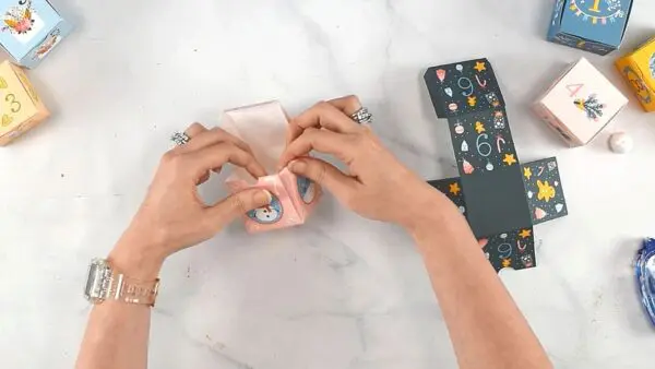 Abbi Kirsten assembles the printed and folded advent calendar boxes into cubes. You can get these templates from CatchingColorflies.com