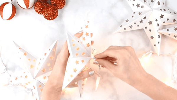 Abbi inserting a small light bulb into the back of a white paper star.