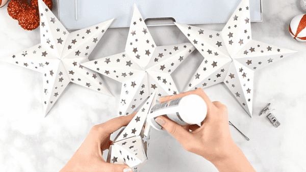Glueing the last pieces together to create a paper star.