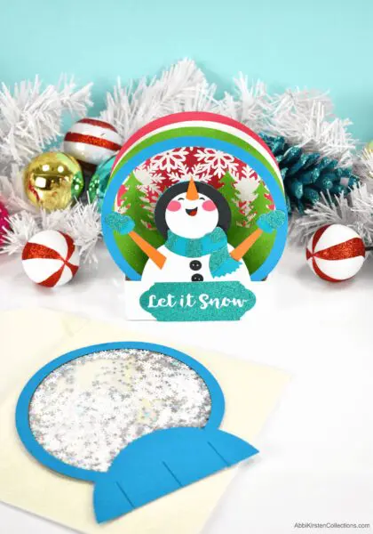 Snowman pop-up card made with Cricut with blue background. 