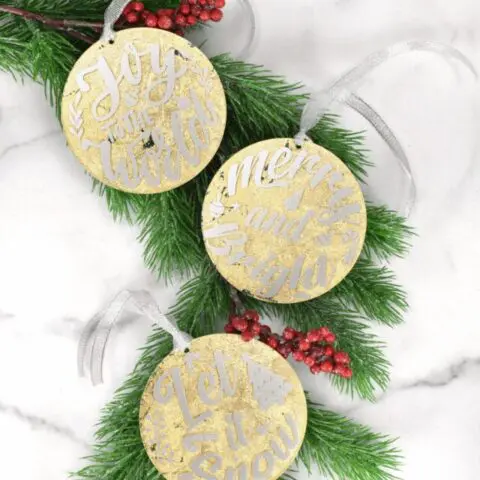 Three DIY gold leaf acrylic Christmas ornaments.