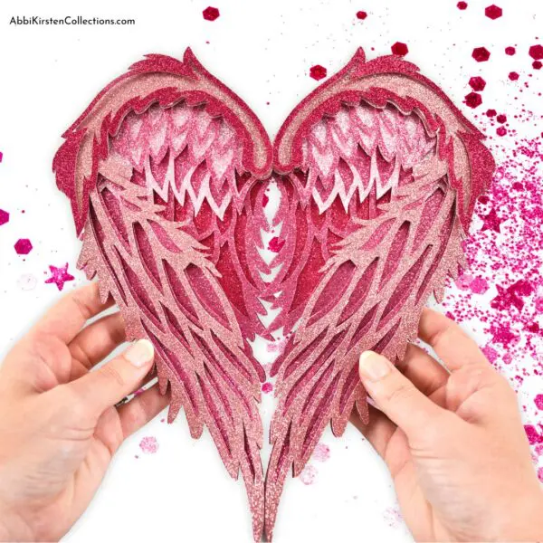 3D paper angel wings craft in pink glitter cardstock. Download free angel wings SVG cut files.